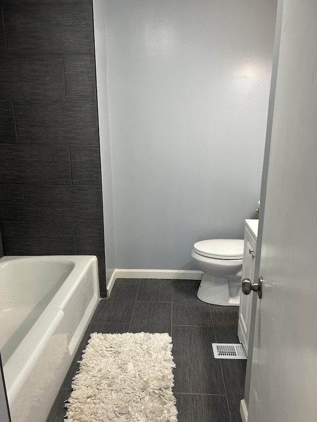 full bath featuring a bathtub, visible vents, toilet, vanity, and baseboards