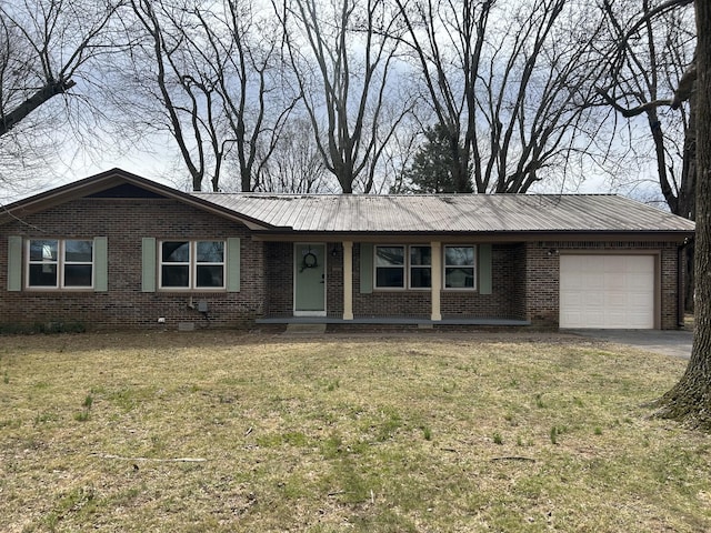 ranch-style house featuring a garage, metal roof, brick siding, and a front yard