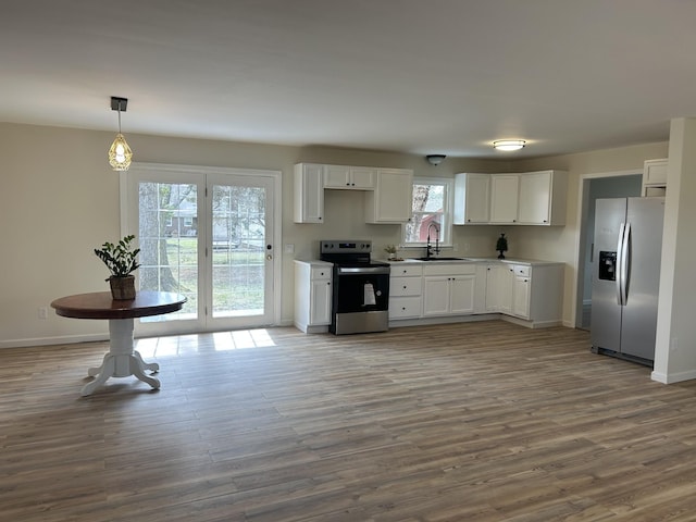 kitchen featuring appliances with stainless steel finishes, white cabinets, a sink, and wood finished floors