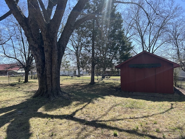 view of yard featuring a storage unit, an outdoor structure, and fence