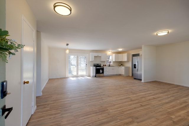 unfurnished living room with light wood-type flooring, a sink, and baseboards