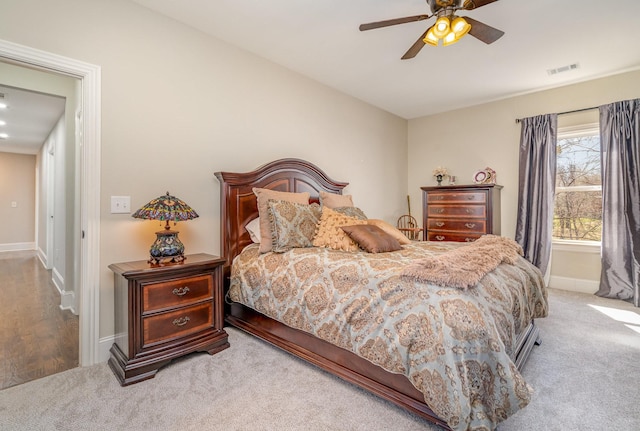 carpeted bedroom with visible vents, baseboards, and a ceiling fan