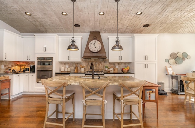 kitchen featuring double oven, brick ceiling, a sink, and dark wood-style floors