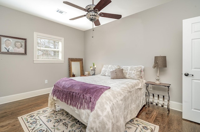 bedroom with a ceiling fan, wood finished floors, visible vents, and baseboards