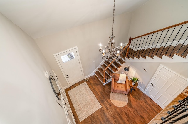 entrance foyer featuring dark wood-style floors, high vaulted ceiling, stairway, a chandelier, and baseboards