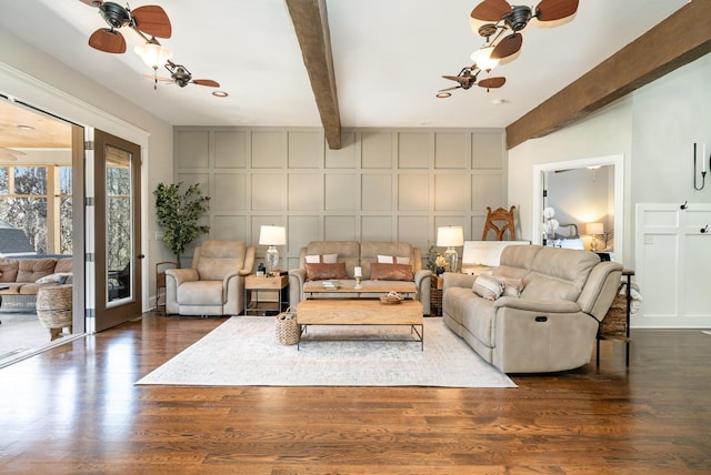 living area with ceiling fan, dark wood-type flooring, beam ceiling, and a decorative wall