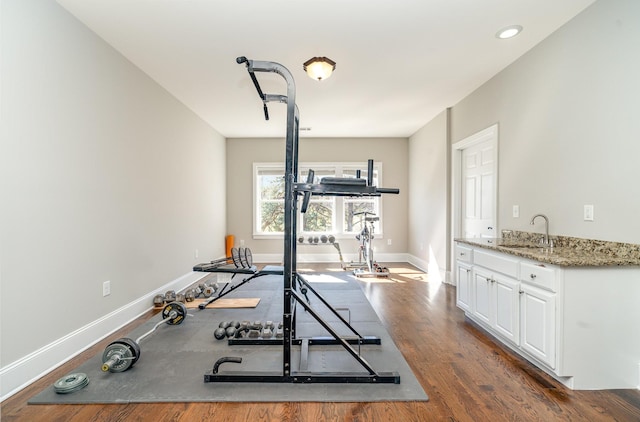 workout area with wood finished floors, recessed lighting, a sink, and baseboards