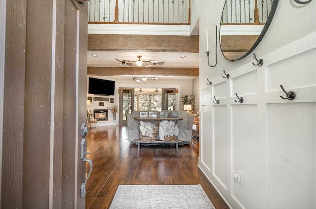 entryway featuring a glass covered fireplace, beamed ceiling, and wood finished floors