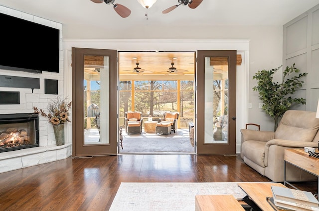 entryway featuring ceiling fan, a fireplace, and wood finished floors