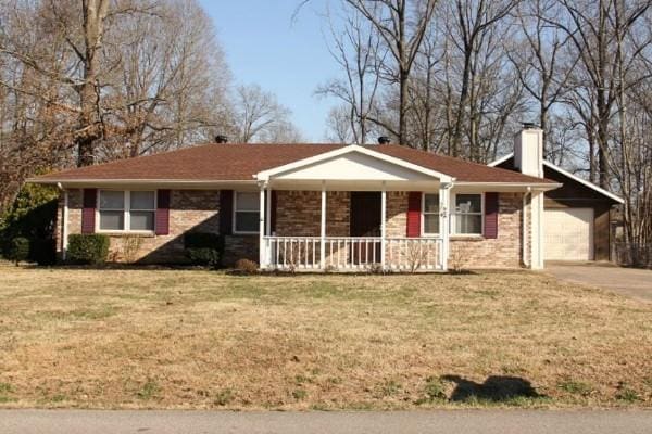 ranch-style house with covered porch, brick siding, driveway, a chimney, and a front yard