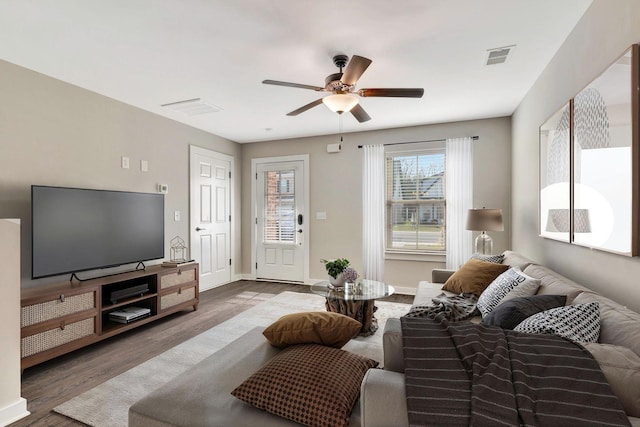 living room featuring wood finished floors, baseboards, ceiling fan, and visible vents