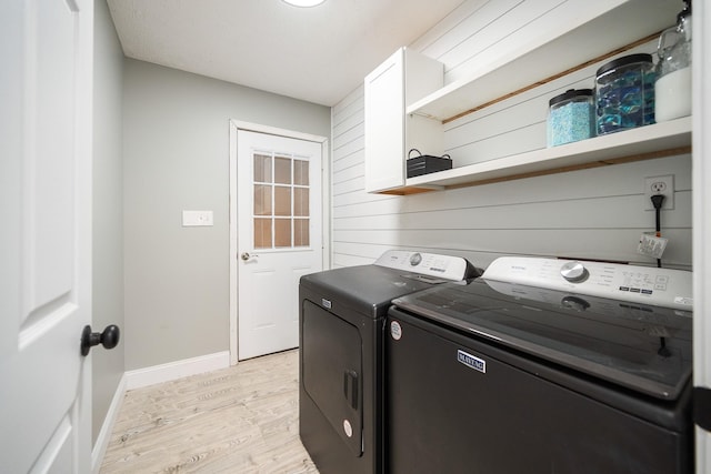 laundry area with laundry area, light wood-type flooring, washing machine and clothes dryer, and baseboards