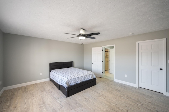 bedroom with light wood-style flooring, baseboards, ceiling fan, and a textured ceiling