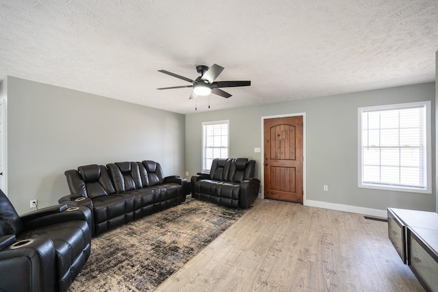 living room featuring visible vents, a textured ceiling, light wood-style flooring, and baseboards