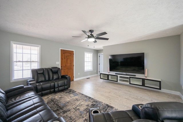 living area with a textured ceiling, ceiling fan, wood finished floors, and baseboards