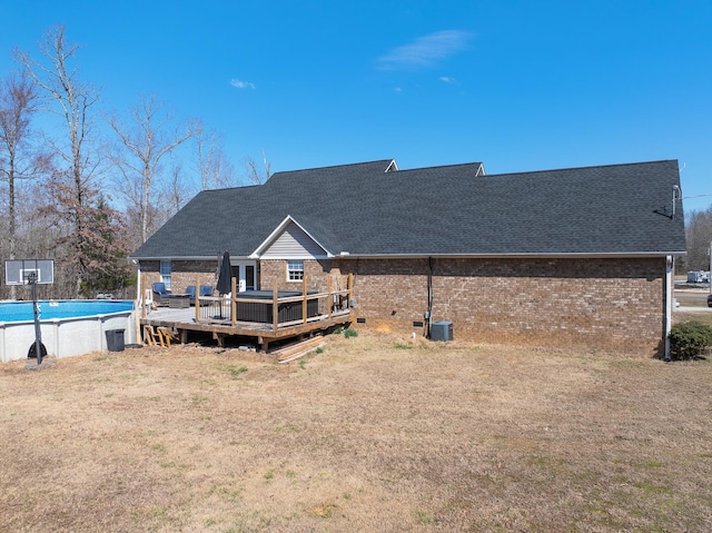 back of property with brick siding, roof with shingles, crawl space, a wooden deck, and an outdoor pool