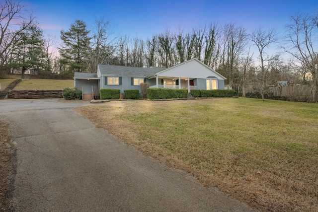 ranch-style house featuring aphalt driveway and a yard