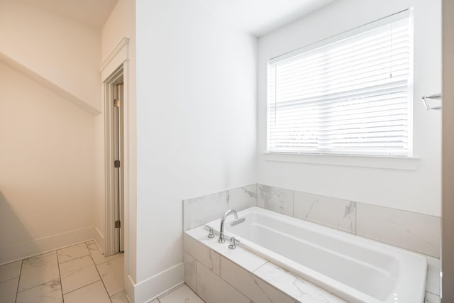 full bathroom featuring marble finish floor, baseboards, and a garden tub