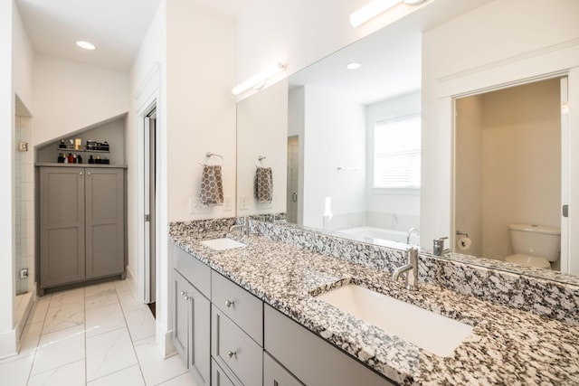 bathroom with toilet, marble finish floor, a garden tub, and a sink