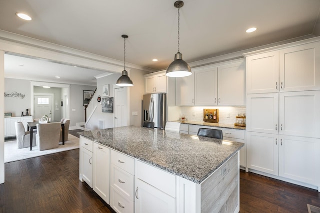 kitchen featuring decorative backsplash, white cabinets, stainless steel fridge with ice dispenser, dark wood-type flooring, and a center island