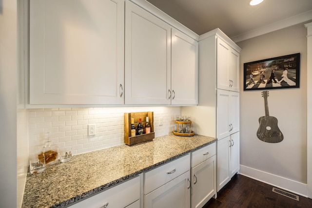 kitchen featuring tasteful backsplash, visible vents, baseboards, light stone counters, and white cabinetry