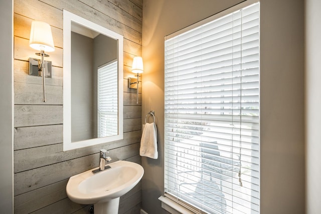 bathroom featuring a sink and wooden walls