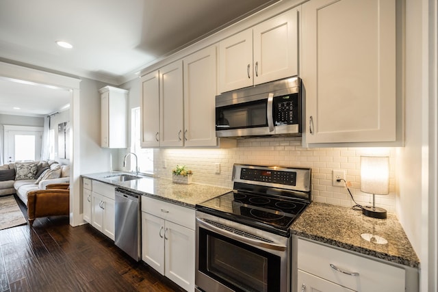 kitchen with light stone countertops, dark wood-style flooring, stainless steel appliances, and a sink