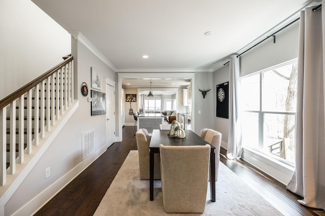 dining area featuring baseboards, wood finished floors, visible vents, and crown molding