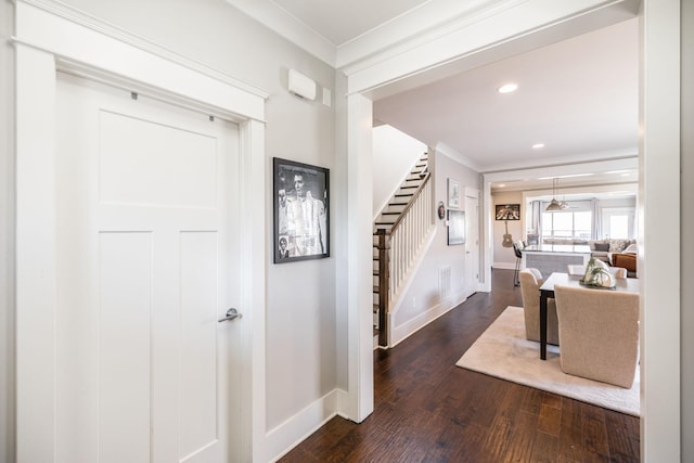 foyer entrance with dark wood-style flooring, ornamental molding, stairway, and baseboards