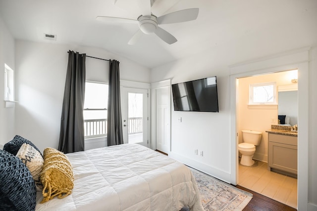 bedroom with baseboards, visible vents, connected bathroom, lofted ceiling, and wood finished floors