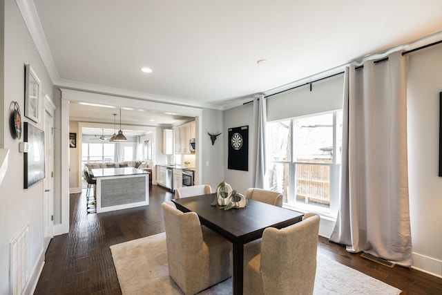 dining space with crown molding, visible vents, and dark wood-type flooring