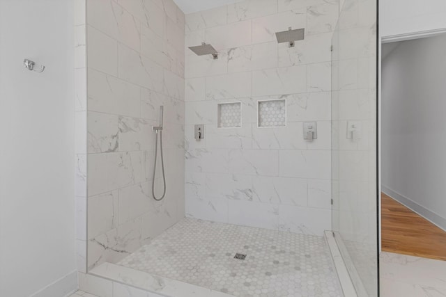 bathroom with baseboards, tiled shower, and wood finished floors