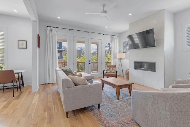 living area with french doors, a fireplace, recessed lighting, ceiling fan, and light wood-type flooring