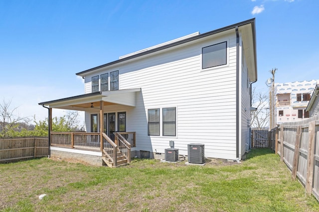 rear view of house featuring a fenced backyard, a lawn, and central air condition unit