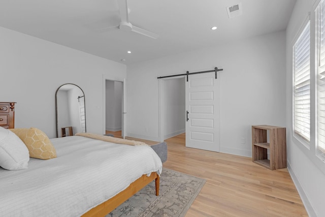 bedroom featuring a barn door, recessed lighting, visible vents, baseboards, and light wood-type flooring