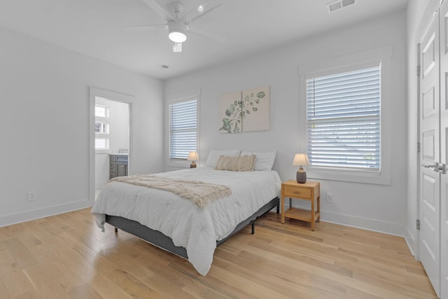 bedroom featuring light wood finished floors, visible vents, ceiling fan, ensuite bath, and baseboards