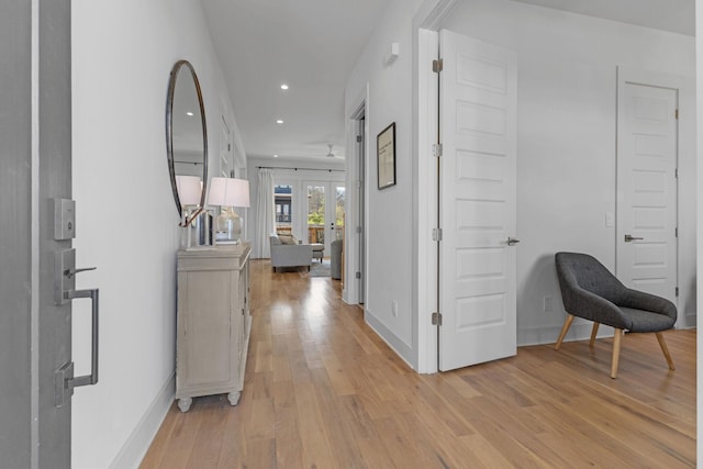 hall featuring baseboards, light wood finished floors, and recessed lighting