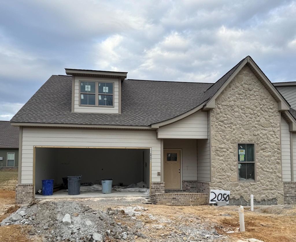 view of front of house with an attached garage, stone siding, a shingled roof, and brick siding