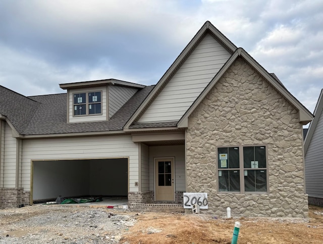 view of front of house with a garage, stone siding, and roof with shingles