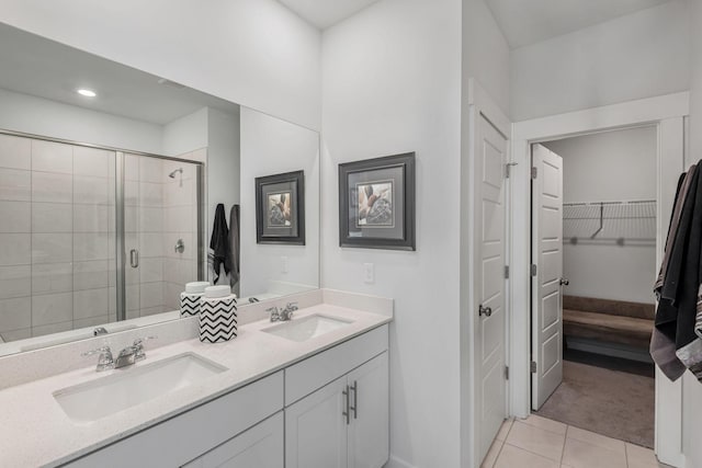 full bath featuring double vanity, a stall shower, a sink, and tile patterned floors