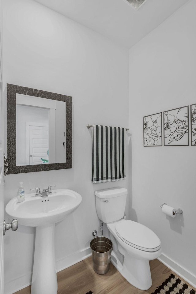 bathroom with toilet, a sink, baseboards, and wood finished floors