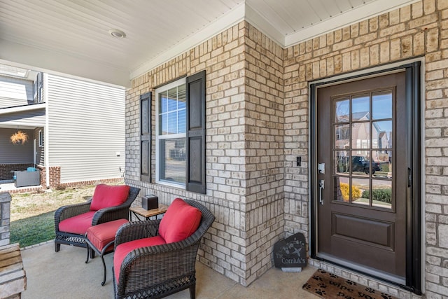 property entrance with a porch and brick siding