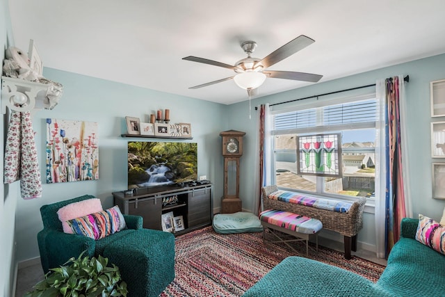 sitting room with ceiling fan and baseboards