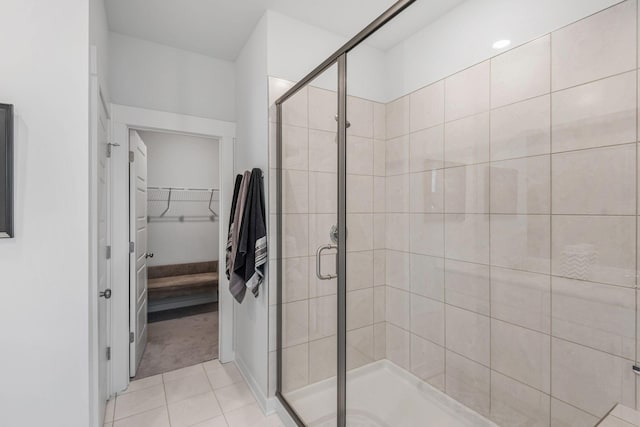 full bath featuring a shower stall, a spacious closet, and tile patterned floors