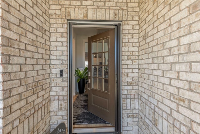 view of exterior entry featuring brick siding