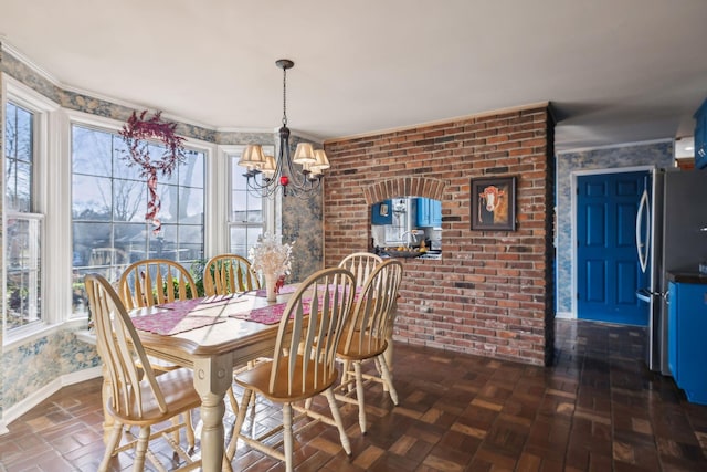 dining area featuring baseboards, brick wall, an inviting chandelier, and a healthy amount of sunlight