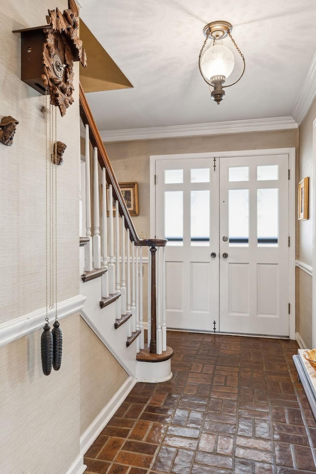 foyer entrance featuring brick floor, baseboards, stairway, and crown molding