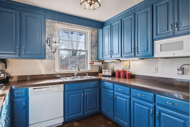 kitchen with dark countertops, white appliances, a sink, and blue cabinetry