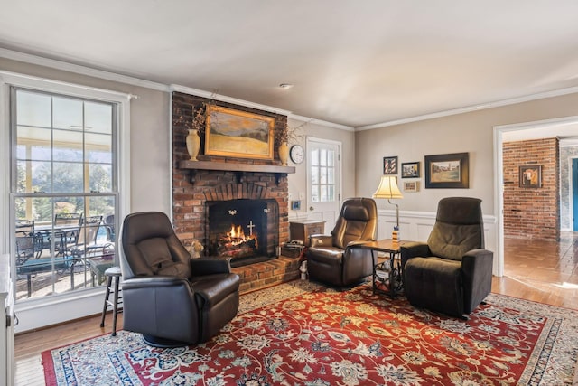 living area featuring a wainscoted wall, a brick fireplace, wood finished floors, and crown molding