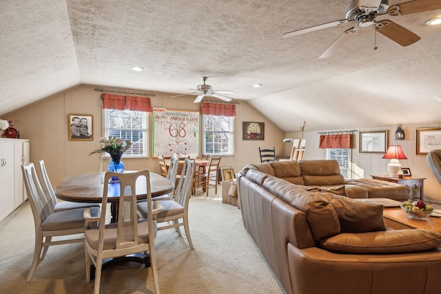 dining room with a textured ceiling, lofted ceiling, and light colored carpet